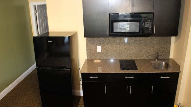 A compact kitchen with a black refrigerator, a microwave, and a sink. - Crown Inn Motel (Yorktown)
