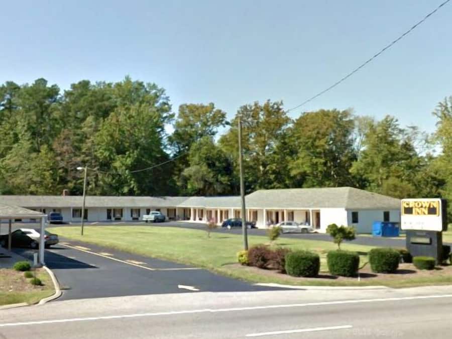 A motel with a single-story structure, a parking lot, and a signboard.
