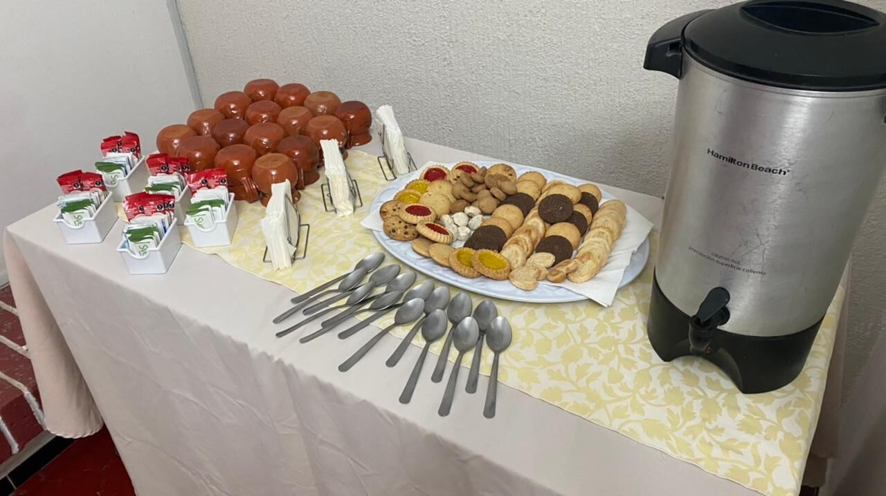 Una mesa de buffet con diversos alimentos, una cafetera y utensilios.