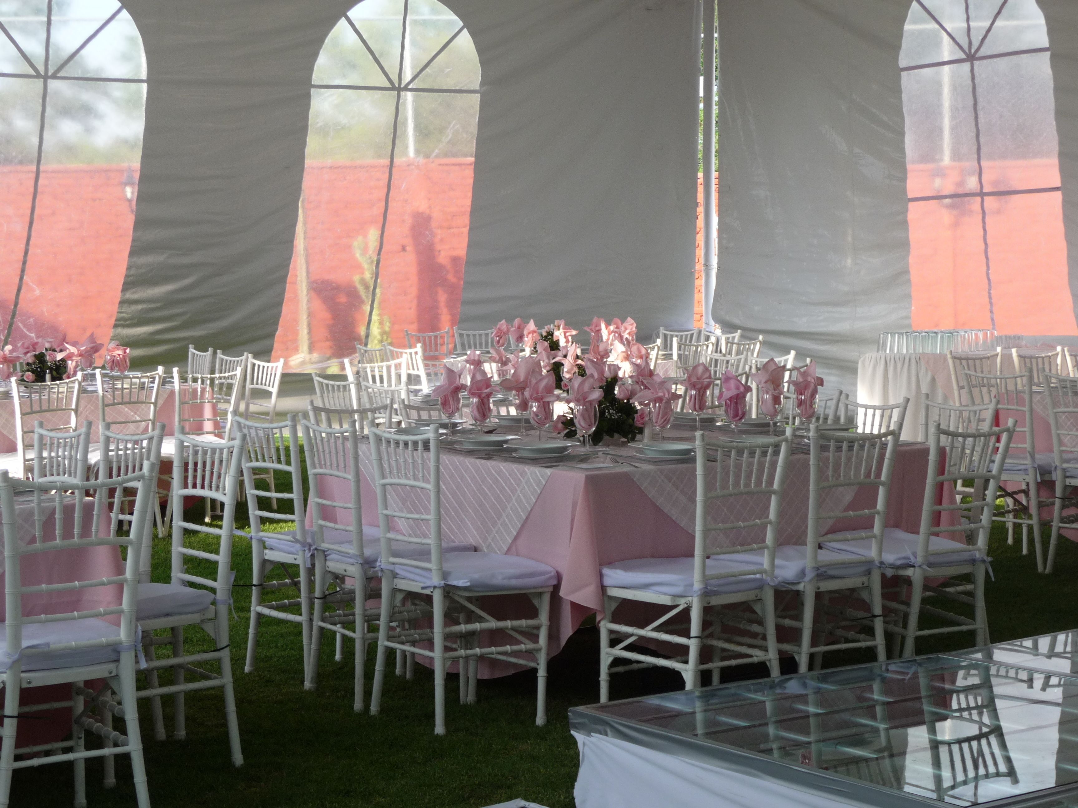 A tented outdoor event space with round tables and white chairs, arranged for a gathering.