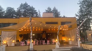 An outdoor dining area with tables and chairs, string lights, and a covered section. - Hotel Finca Las Hortensias (Tepotzotlán)