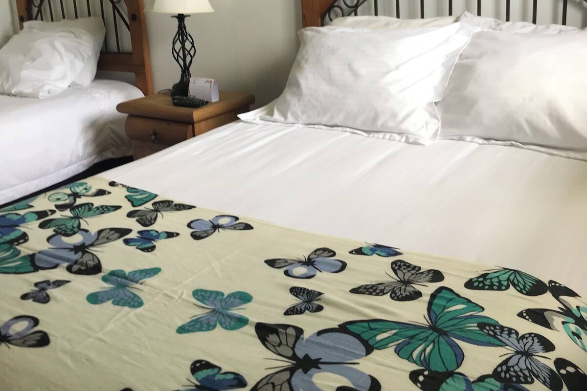 Una camera d'albergo con due letti, una testiera in legno, un comodino con una lampada e un quadro appeso al muro.