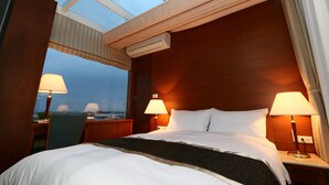 A hotel room with a large bed, two bedside lamps, a window with a view, and an air conditioning unit. - Aleex Villa (Yuanshan)
