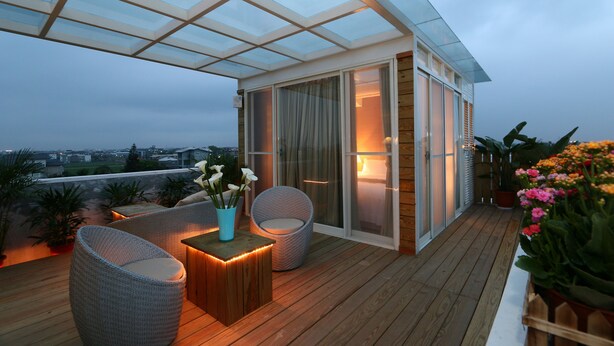 A balcony with wicker furniture, a glass enclosure, and potted plants. - Aleex Villa (Yuanshan)