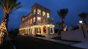 A multi-story hotel with a grand entrance, a balcony on the upper floor, and a well-lit facade. - Aleex Villa (Yuanshan)