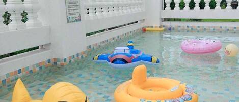 An indoor swimming pool with colorful tiles, inflatable ducks, and a white balustrade.