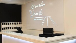 Una mesa de recepción con un letrero que dice "El sueño de Jemik HOTEL RESTAURANTE" y una proyección de una estructura tipo tienda de campaña.