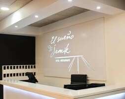 Una mesa de recepción con un letrero que dice "El sueño de Jemik HOTEL RESTAURANTE" y una proyección de una estructura tipo tienda de campaña.