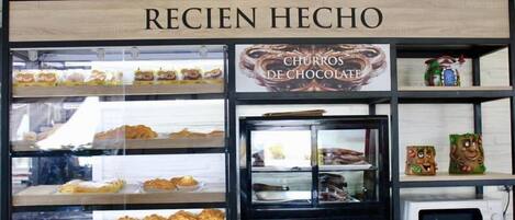 A bakery display with a sign reading "RECEN HECHO" and "CHURROS DE CHOCOLAT".