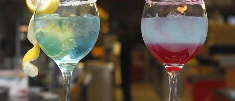 Two cocktails in stemmed glasses with a lemon garnish on the left and a pink rimmed glass on the right.