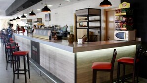 Un área de bar moderna con barra, asientos y una exhibición de aperitivos.