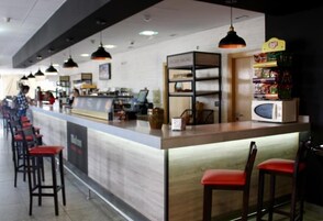 Un área de bar moderna con barra, asientos y una exhibición de aperitivos.