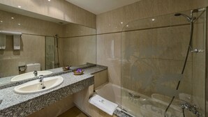 A modern bathroom with two sinks, a glass shower enclosure, and a bathtub. - Motel Cancun León (Ardon)