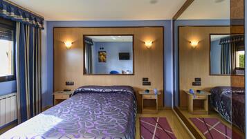 Ein Hotelzimmer mit Bett, Schreibtisch, Stuhl, Spiegel und einem Fenster mit Vorhängen.