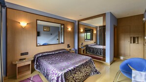 A modern hotel room with a large bed, a desk, a chair, and a mirror. - Motel Cancun León (Ardon)