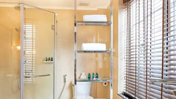 A modern bathroom with a glass-enclosed shower, a freestanding bathtub, and shelves with toiletries.