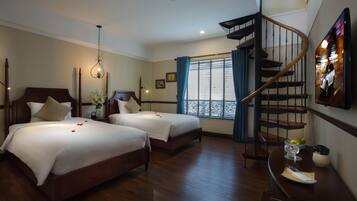 A hotel room with two beds, a wooden staircase, and a window with curtains.