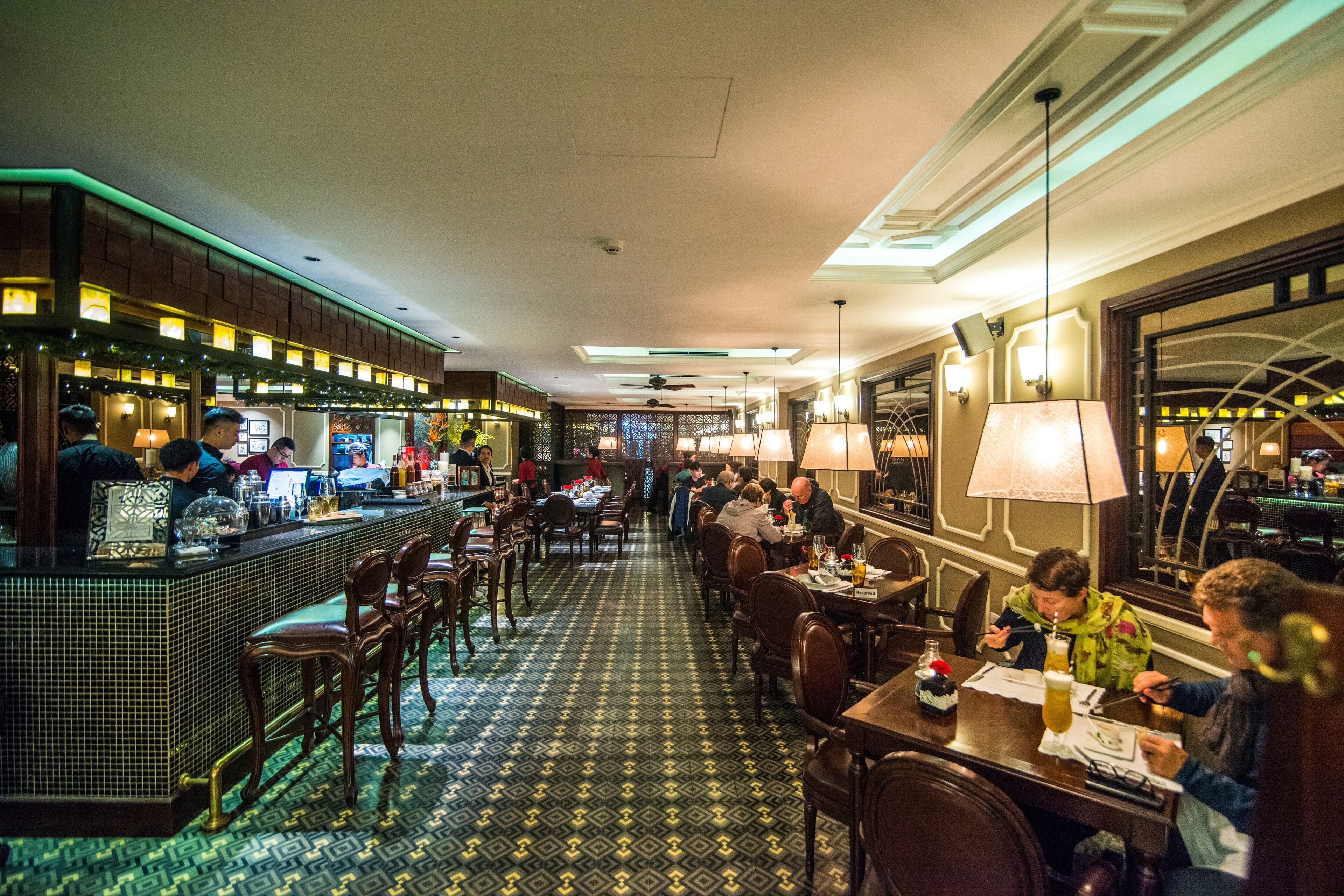 A restaurant with a bar area, multiple tables, and chairs.