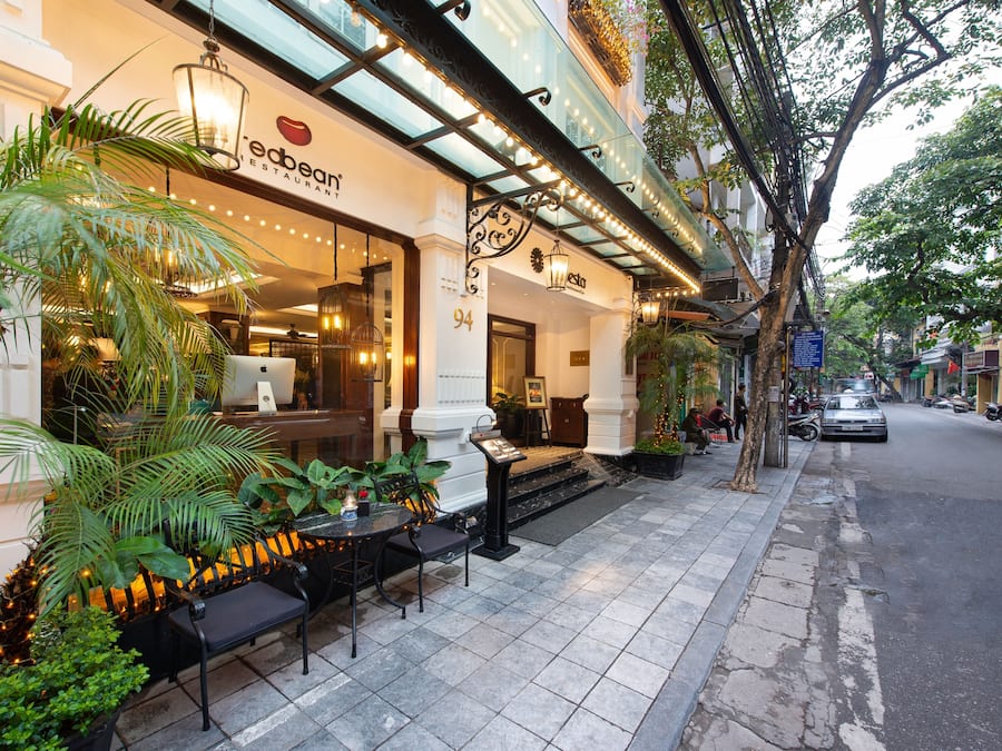 An outdoor seating area with tables and chairs, a palm tree, and a building with a sign that reads "ebetan restaurant".