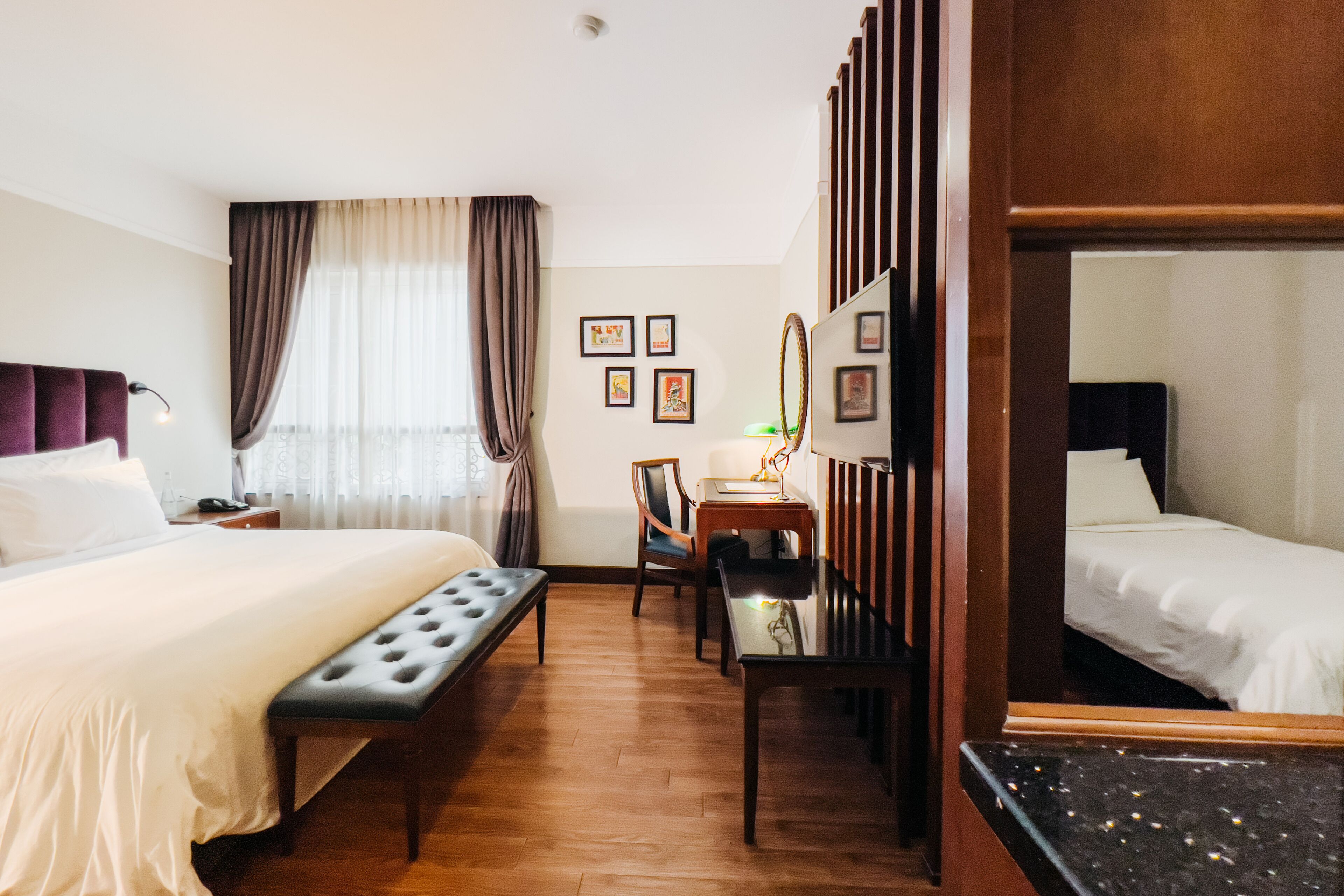 Habitació d'hotel amb un llit gran, una panxa, un escriptori amb una làmpada i un mirall.