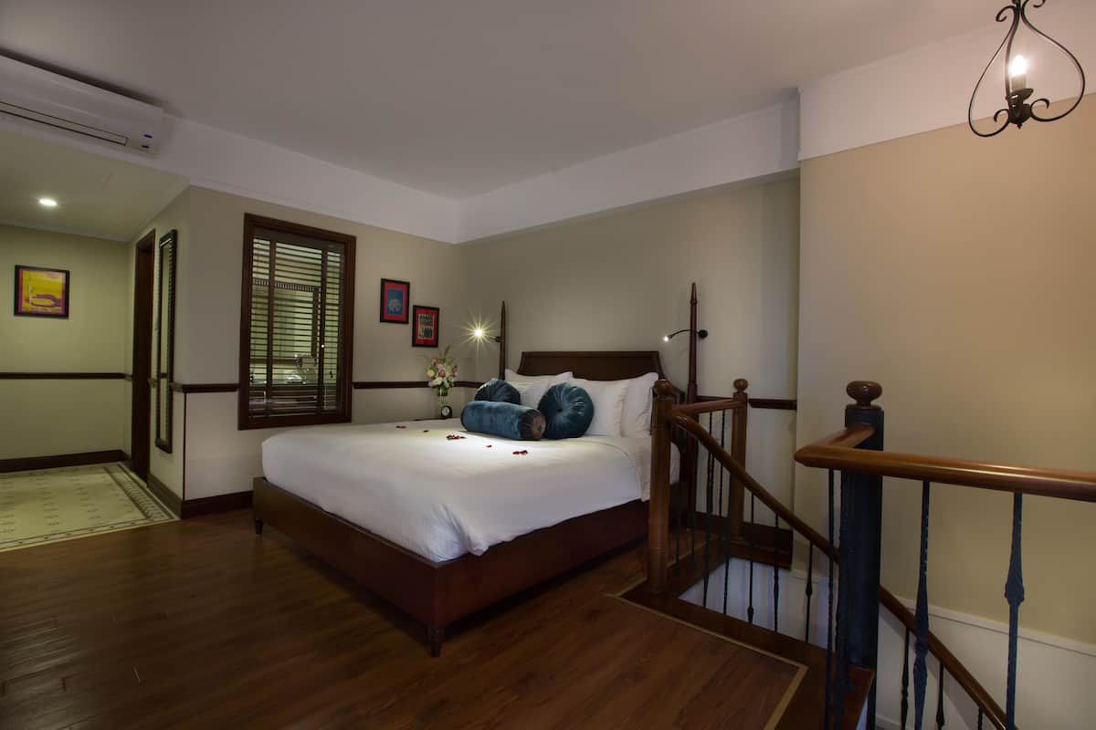 A bedroom with a wooden bed, a nightstand, and a window with blinds.