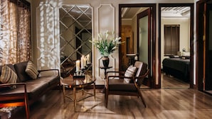 Una habitación con sofá, sillón y una mesita con velas y una planta.