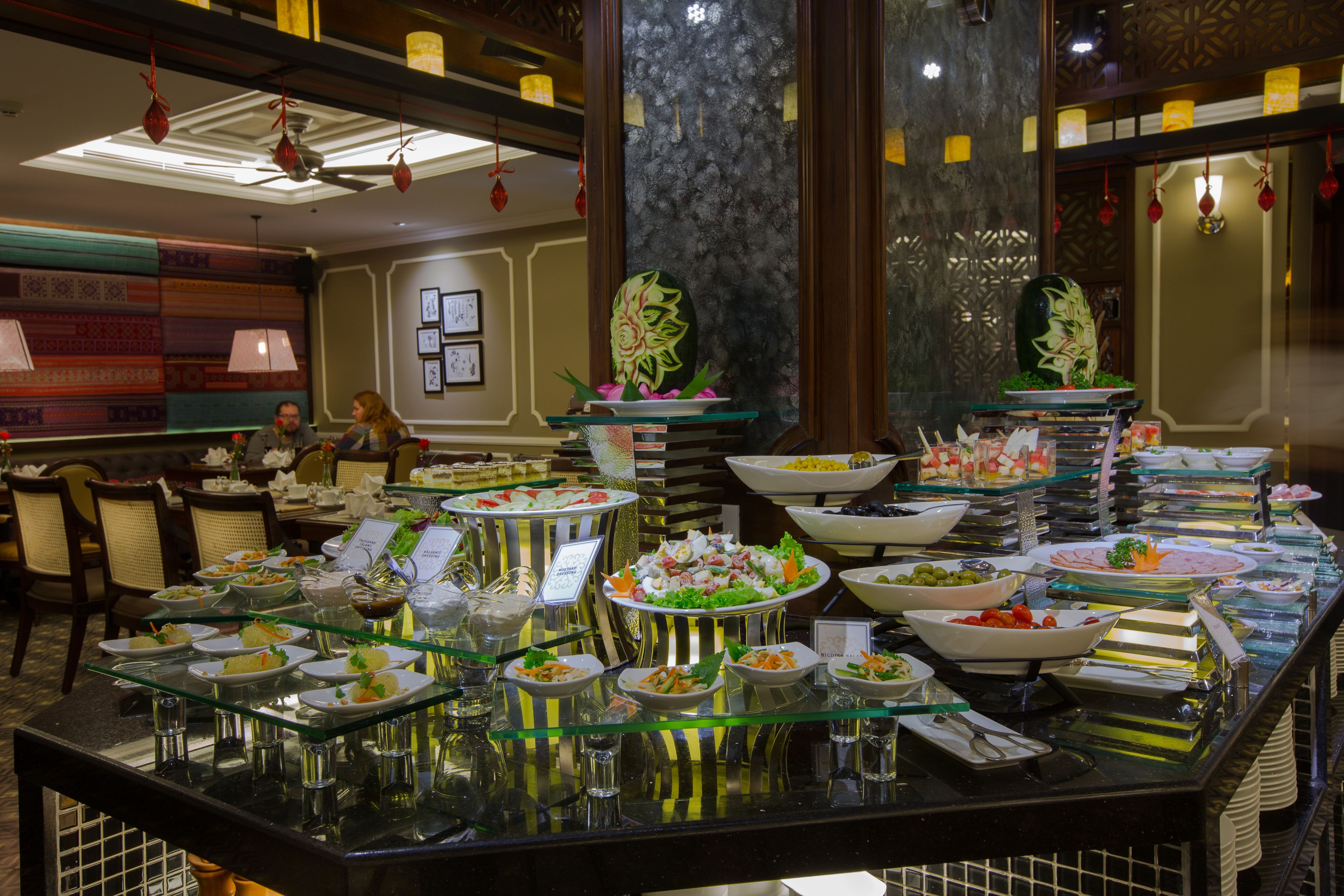 A buffet with various dishes and a seating area with chairs and tables.