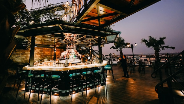 Un área de bar al aire libre con mostrador, asientos y vistas de la ciudad.