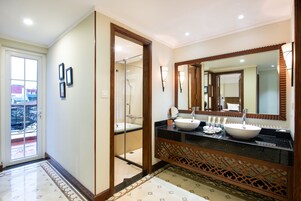 A modern bathroom with a large mirror, two sinks, and a shower area.
