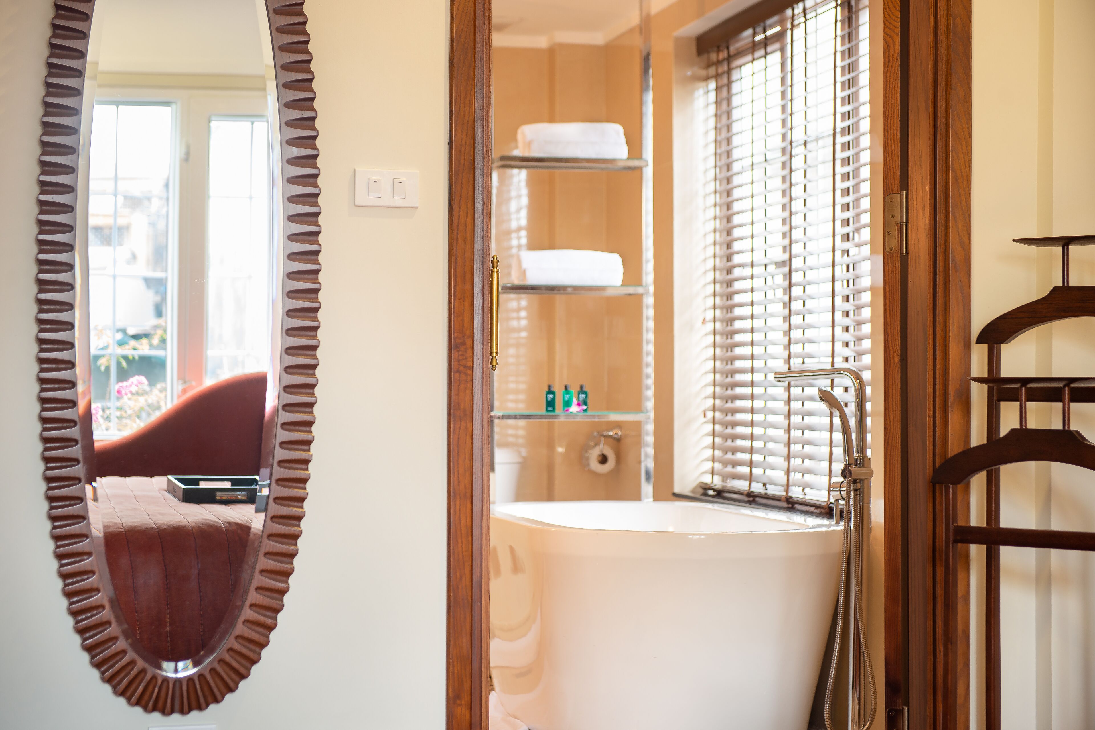 A bathroom with a bathtub, a shower, and a shelf with toiletries.