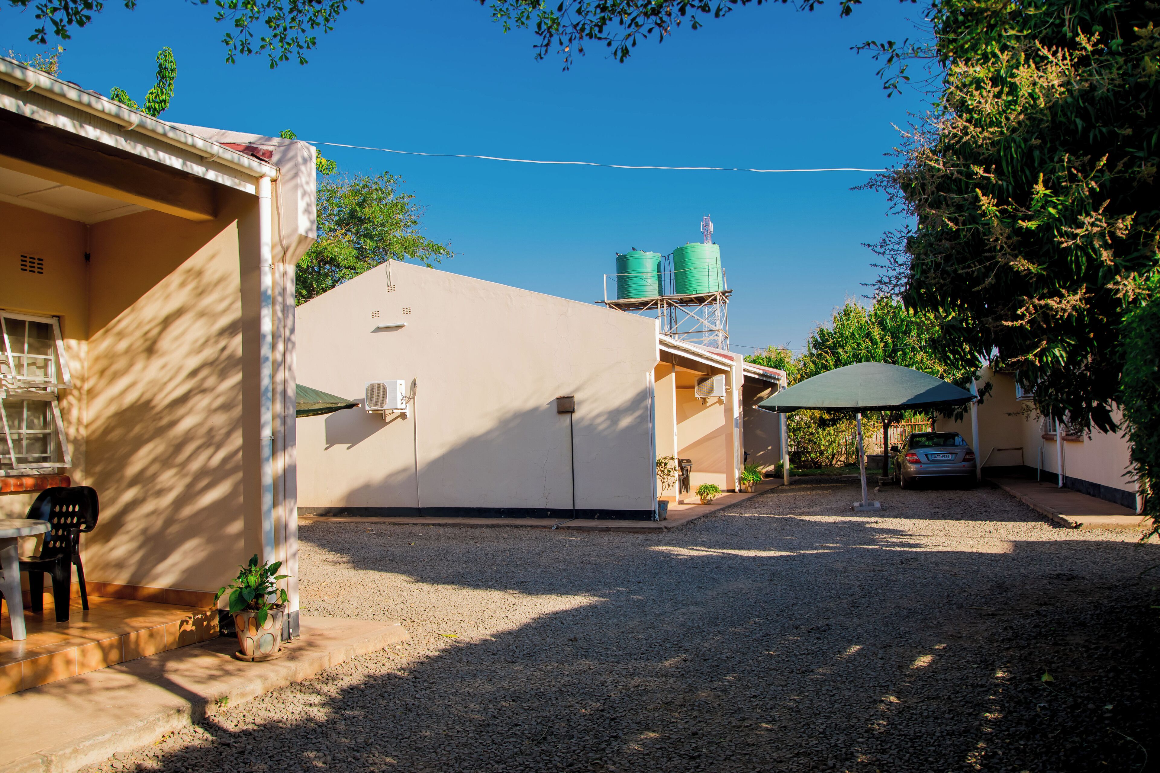 Un quartier résidentiel avec une maison, une voiture et deux réservoirs d’eau verts sur un toit.