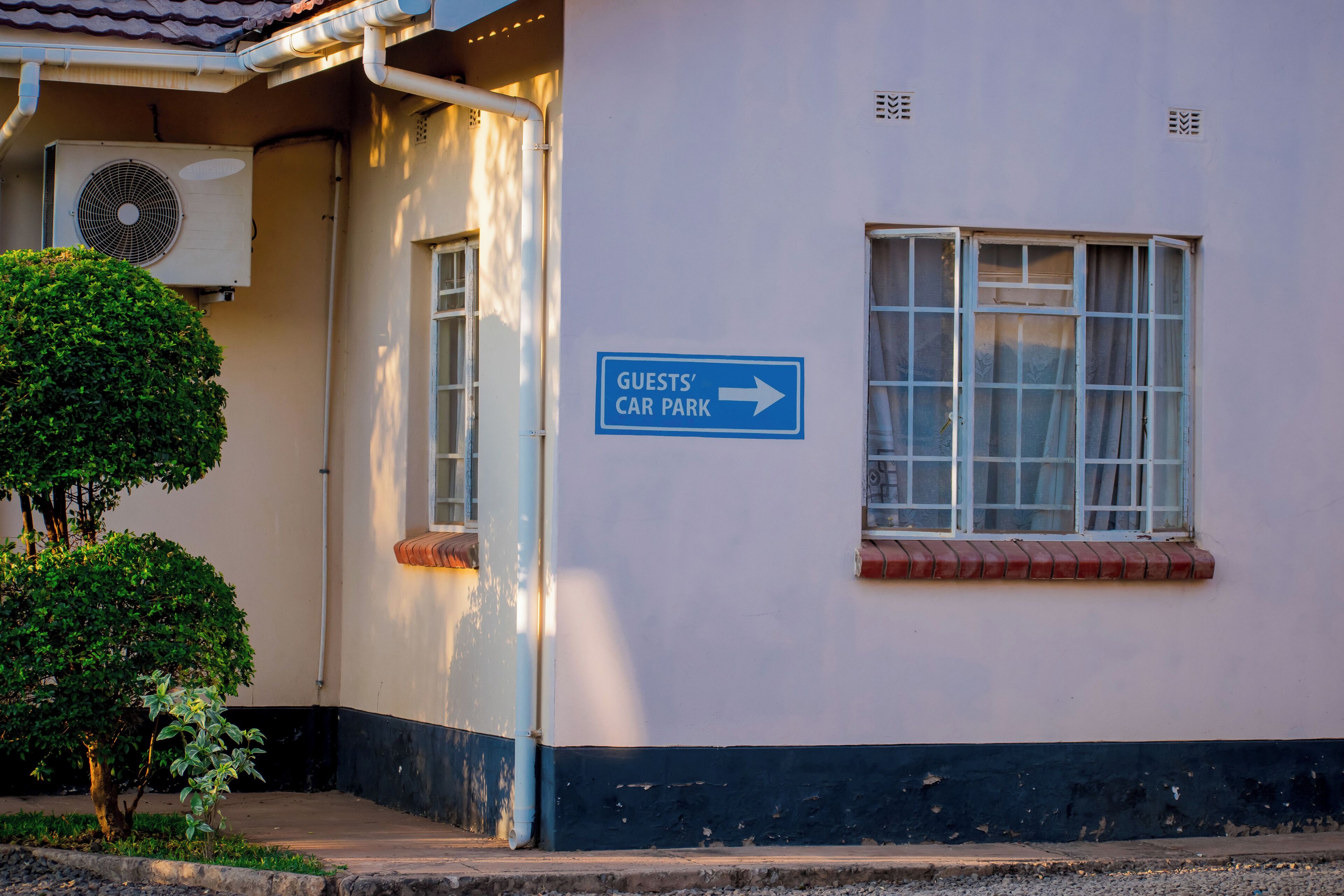A building with a sign indicating a guests' car park to the right.