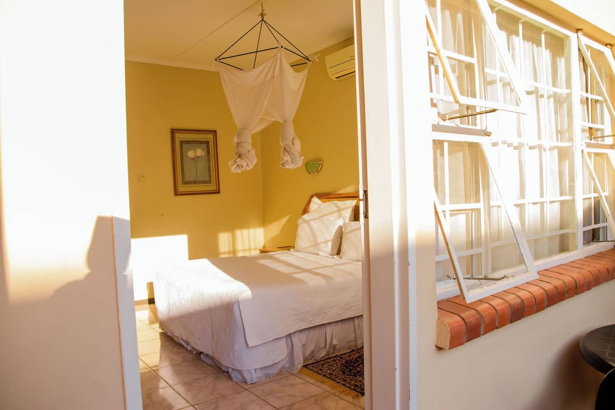 A bedroom with a bed, a window with a view, and a hanging canopy.