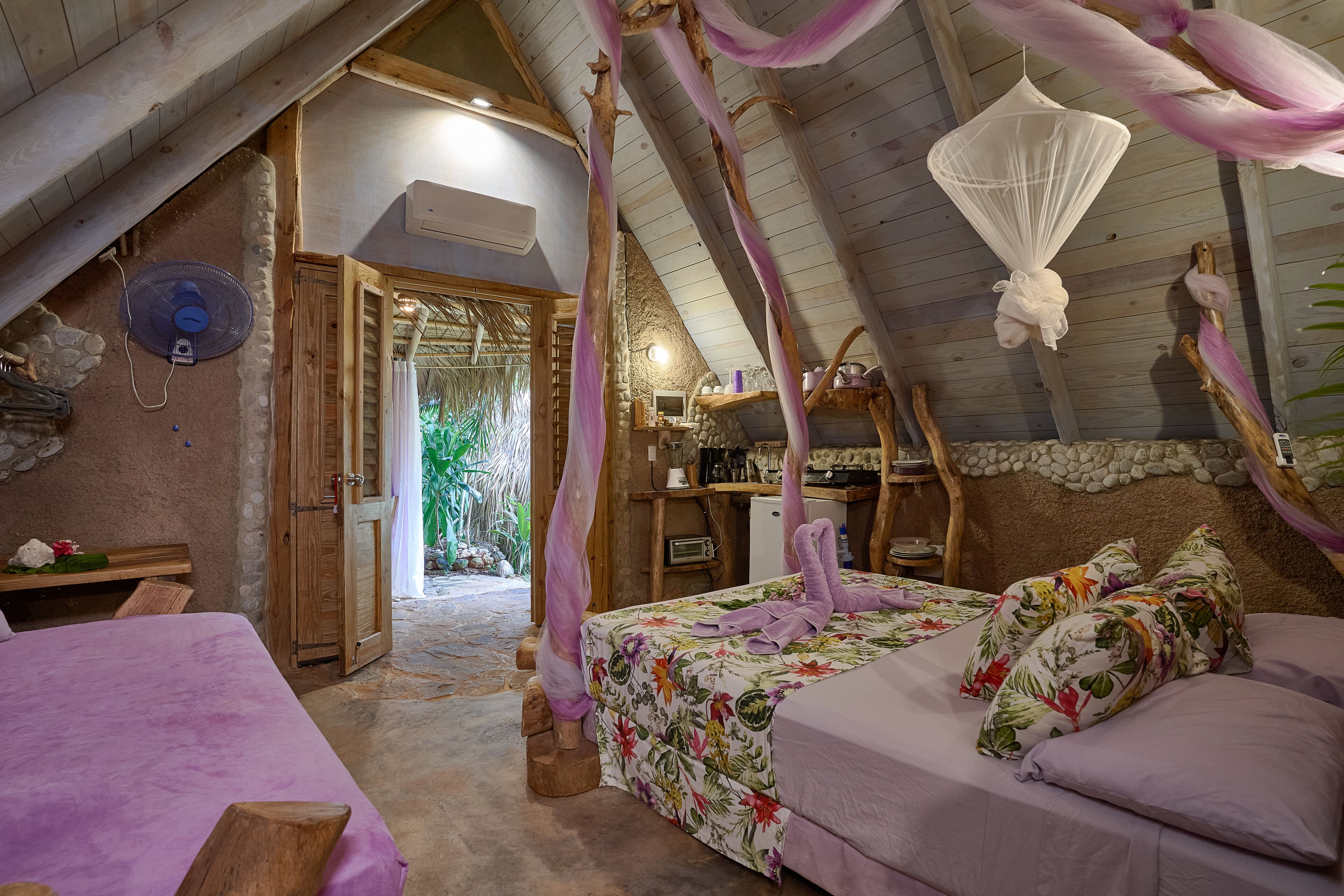 A cozy bedroom with a bed, a wooden desk, and a small bathroom.