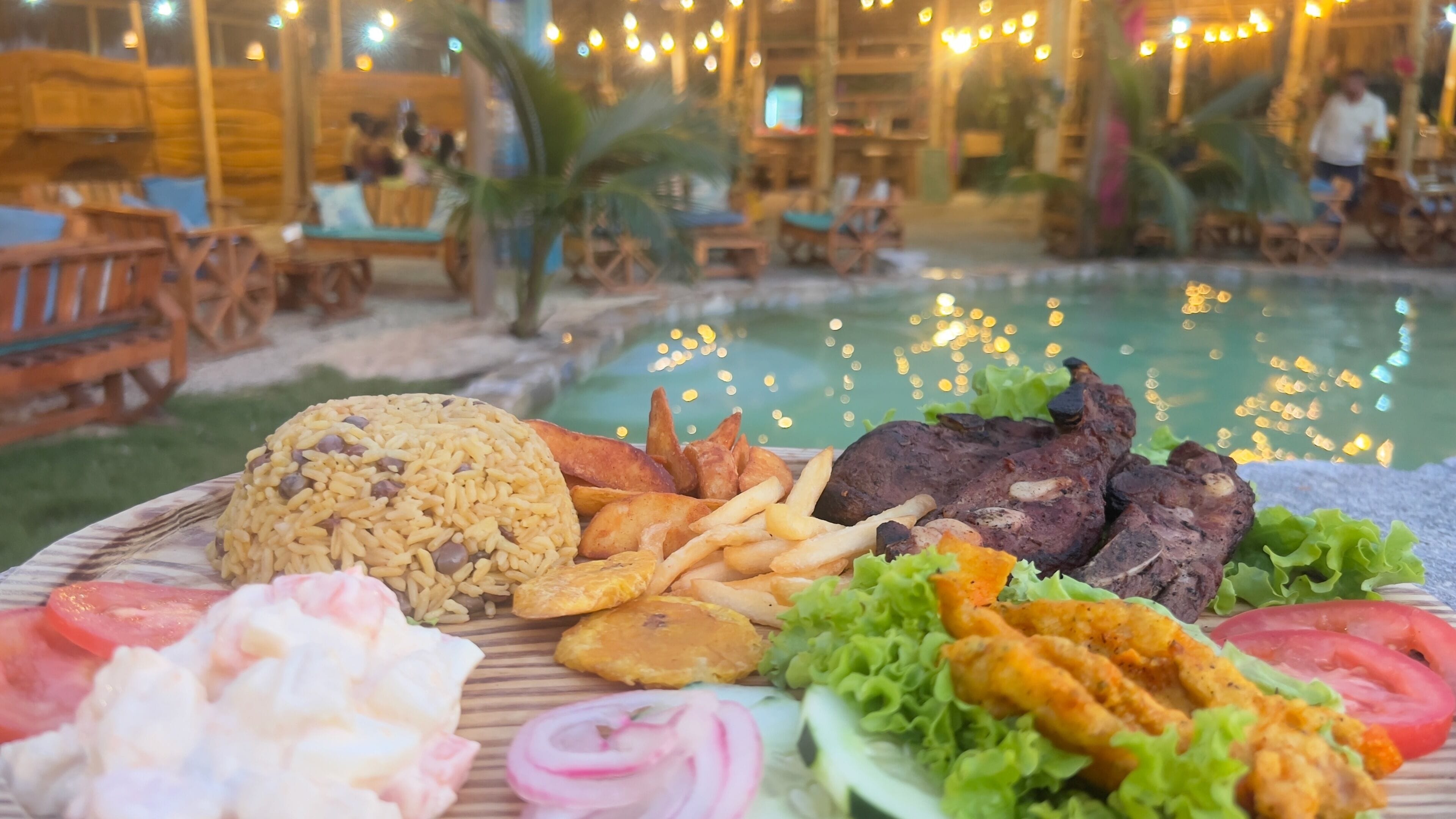 A dining table with a variety of food items including rice, fries, meat, and vegetables.
