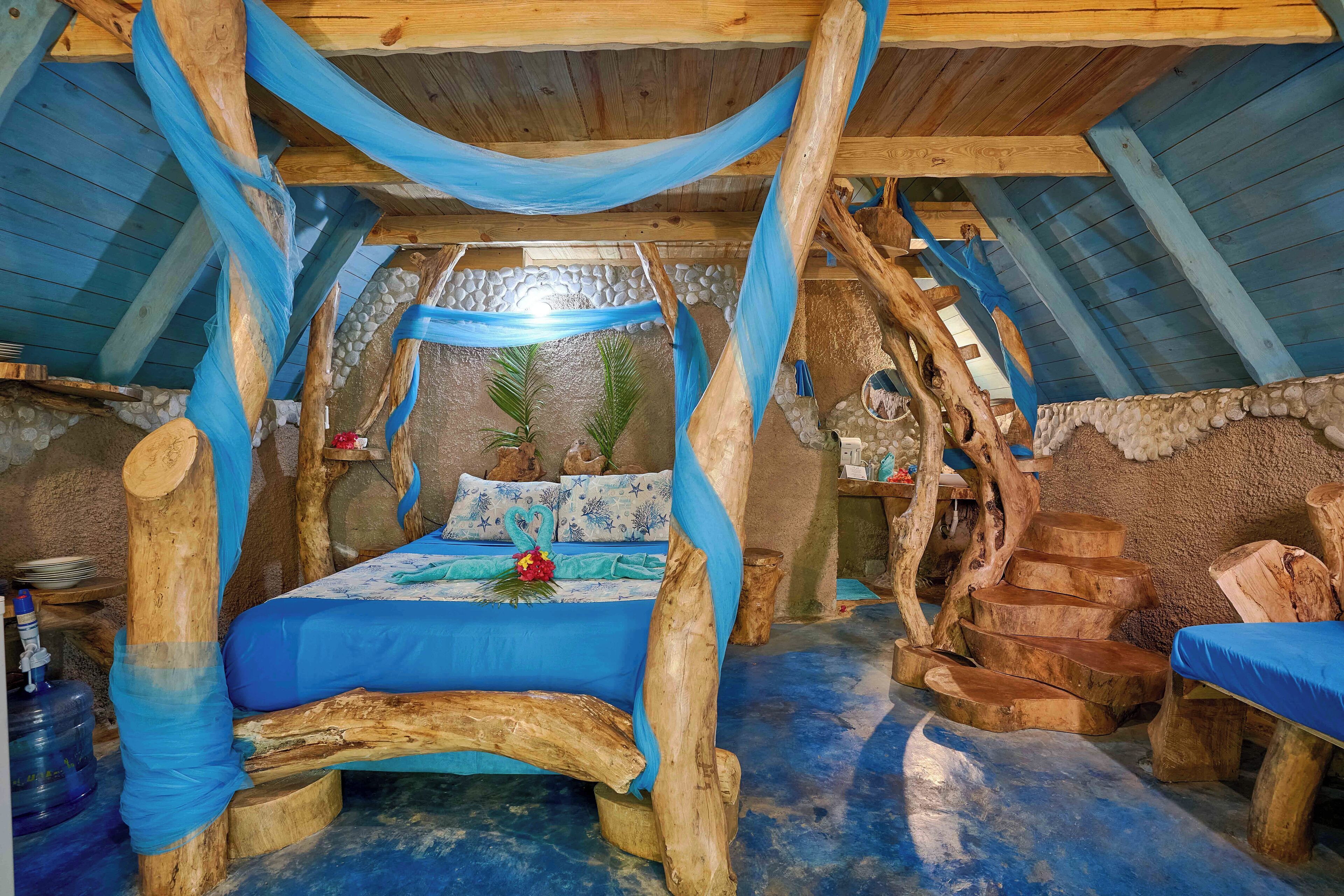Une pièce rustique en bois, dotée d’un lit à baldaquin, de murs en pierre et d’une cheminée en pierre naturelle.