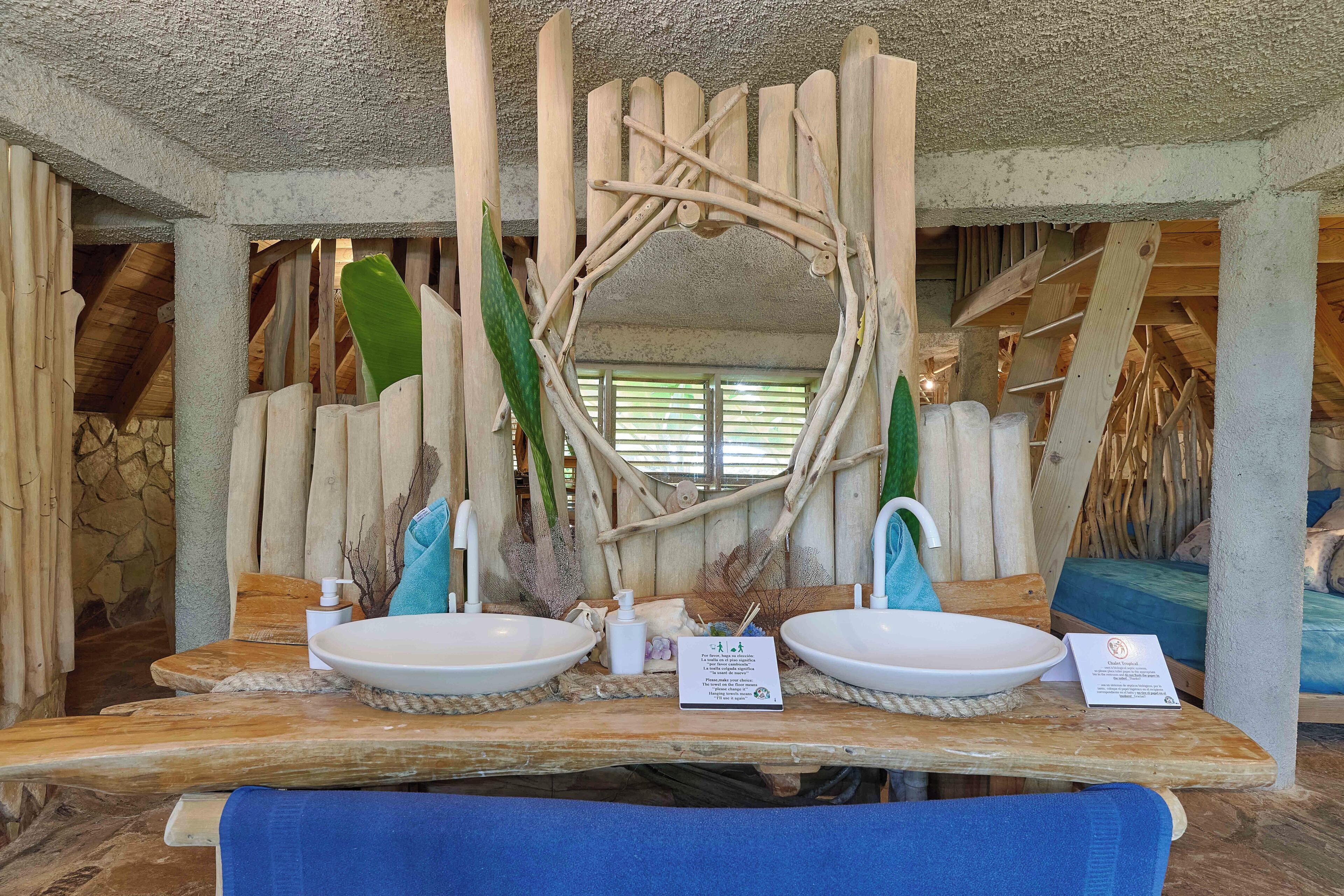 A wooden vanity with two sinks, a mirror, and a towel.