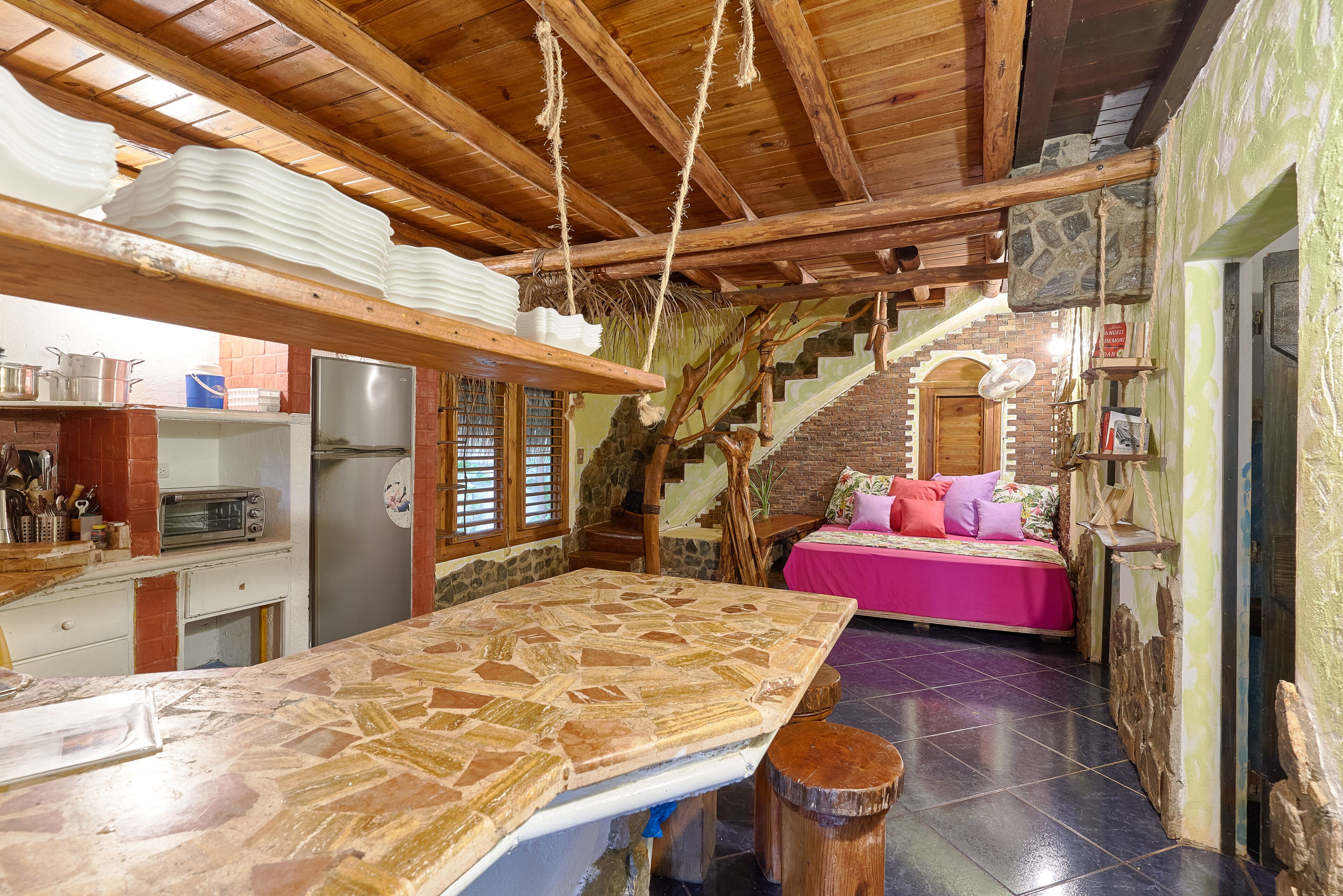 A rustic kitchen with a tiled countertop, a refrigerator, and a toaster.