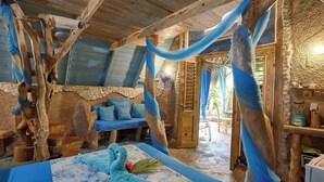 A rustic room with a wooden ceiling, a stone wall, and a bed with blue bedding. -  CHALET TROPICAL Hotel & Pool Bar Restaurant (Las Galeras)