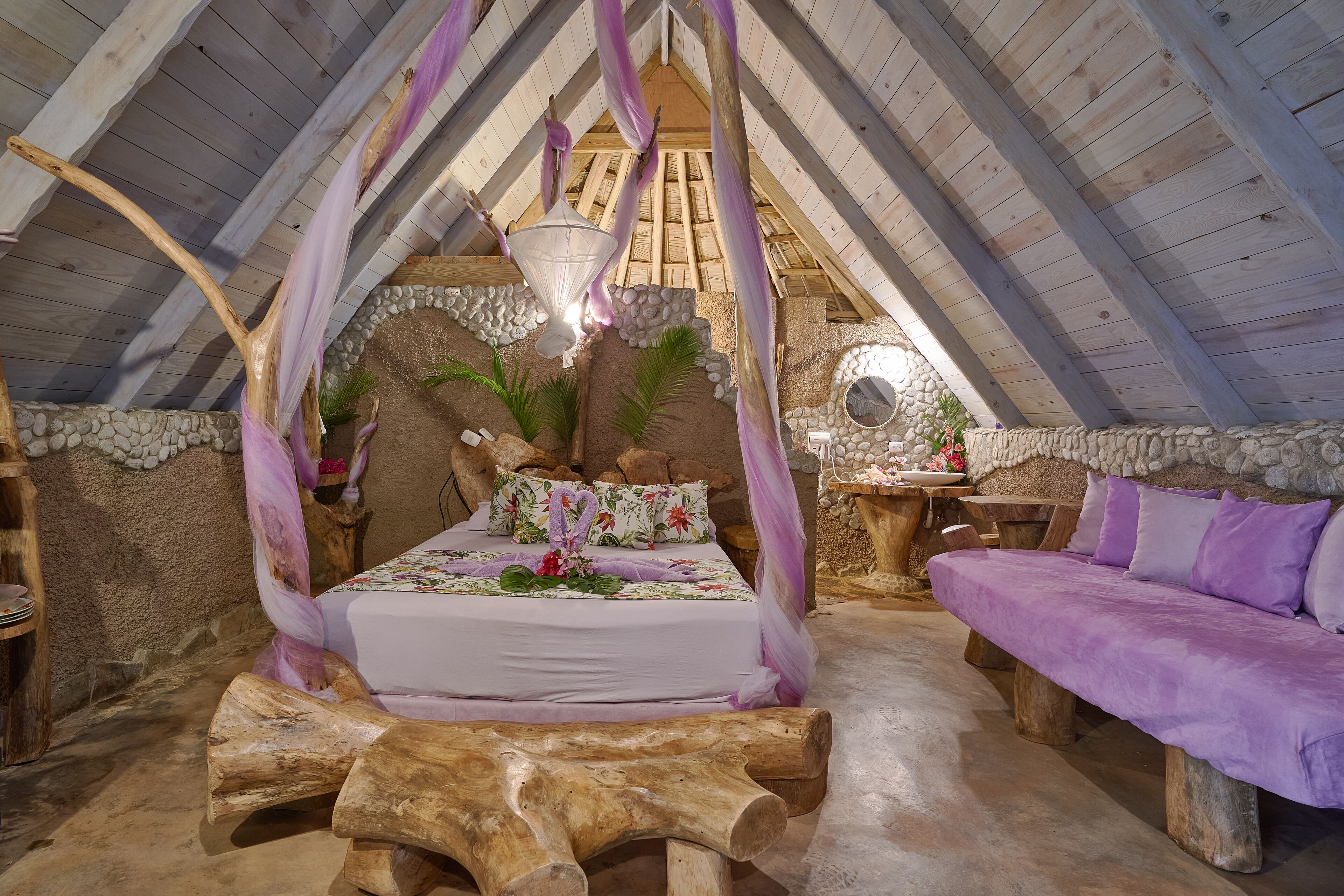 Un dormitorio acogedor en el ático con una cama, un banco de madera y una pared de piedra.