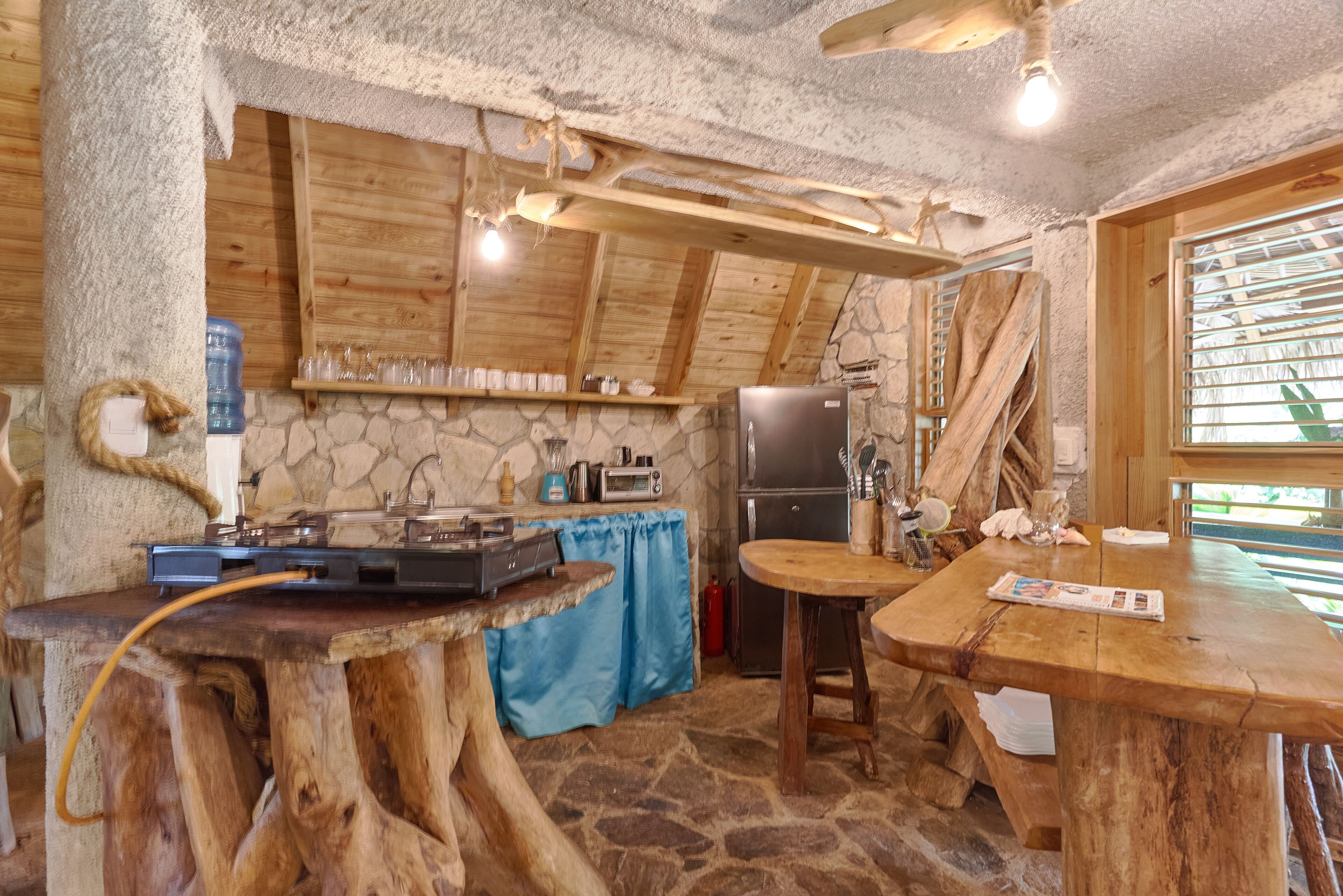 A rustic kitchen with wooden beams, stone walls, and a stone floor.