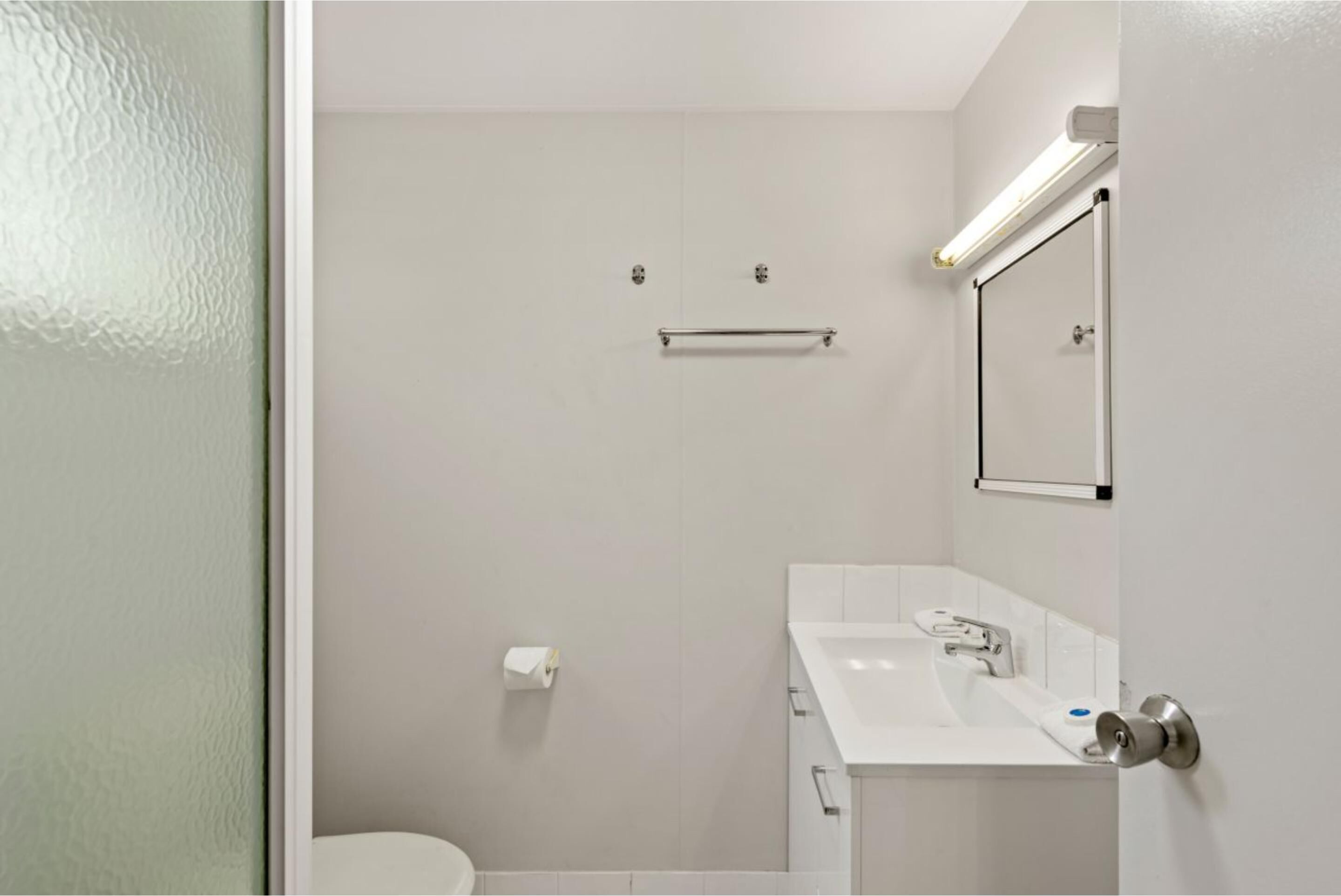 Un baño moderno con inodoro, lavamanos y espejo.