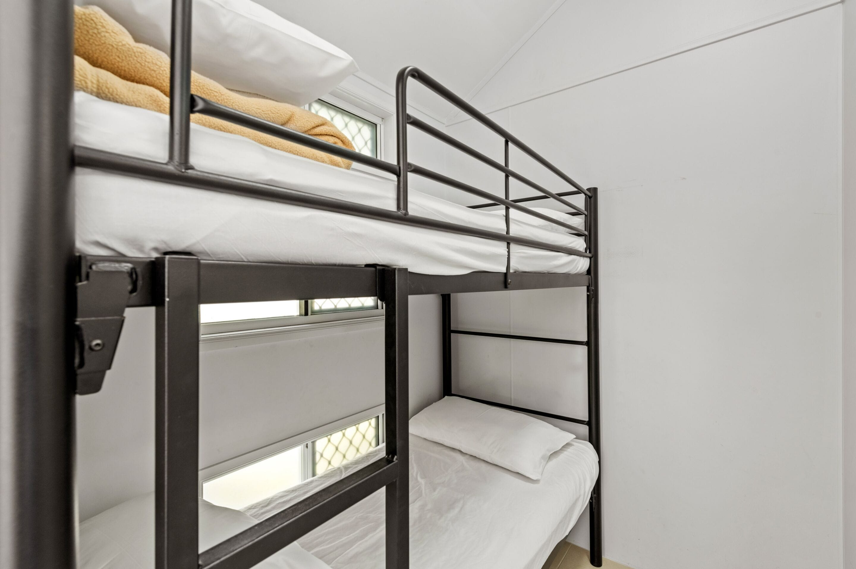 A bunk bed with a metal frame and white bedding.