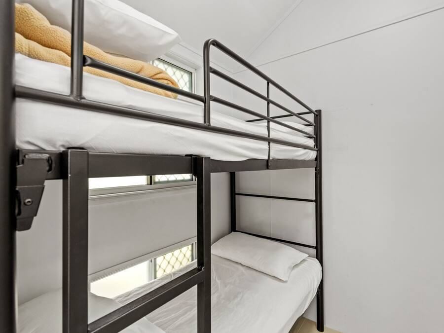 A bunk bed with a metal frame and white bedding.