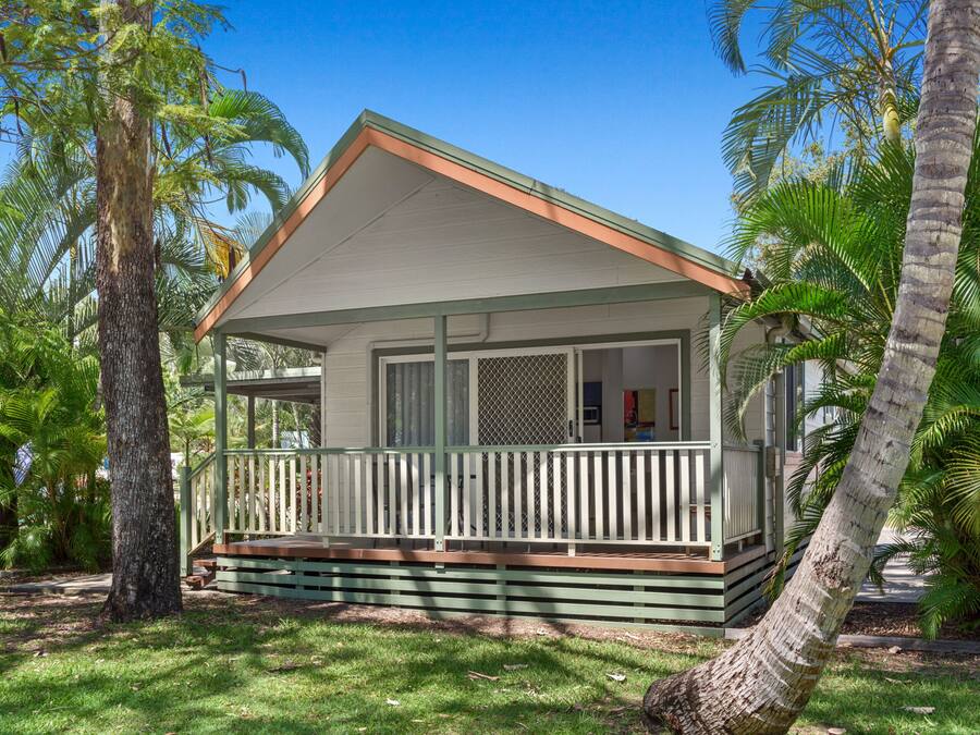 Una casa a un piano con veranda, circondata da palme.