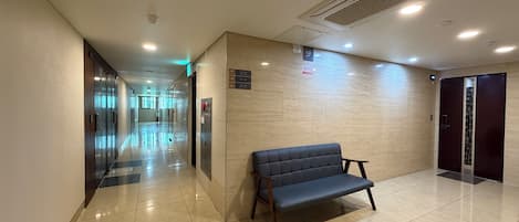 A hotel lobby with a bench, a reception desk, and an elevator.