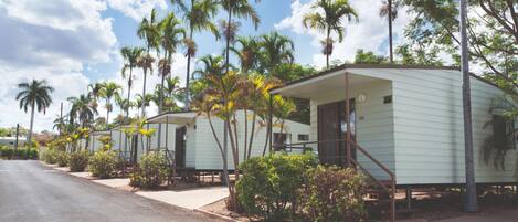 A row of mobile homes with a paved road in front, surrounded by palm trees and greenery.