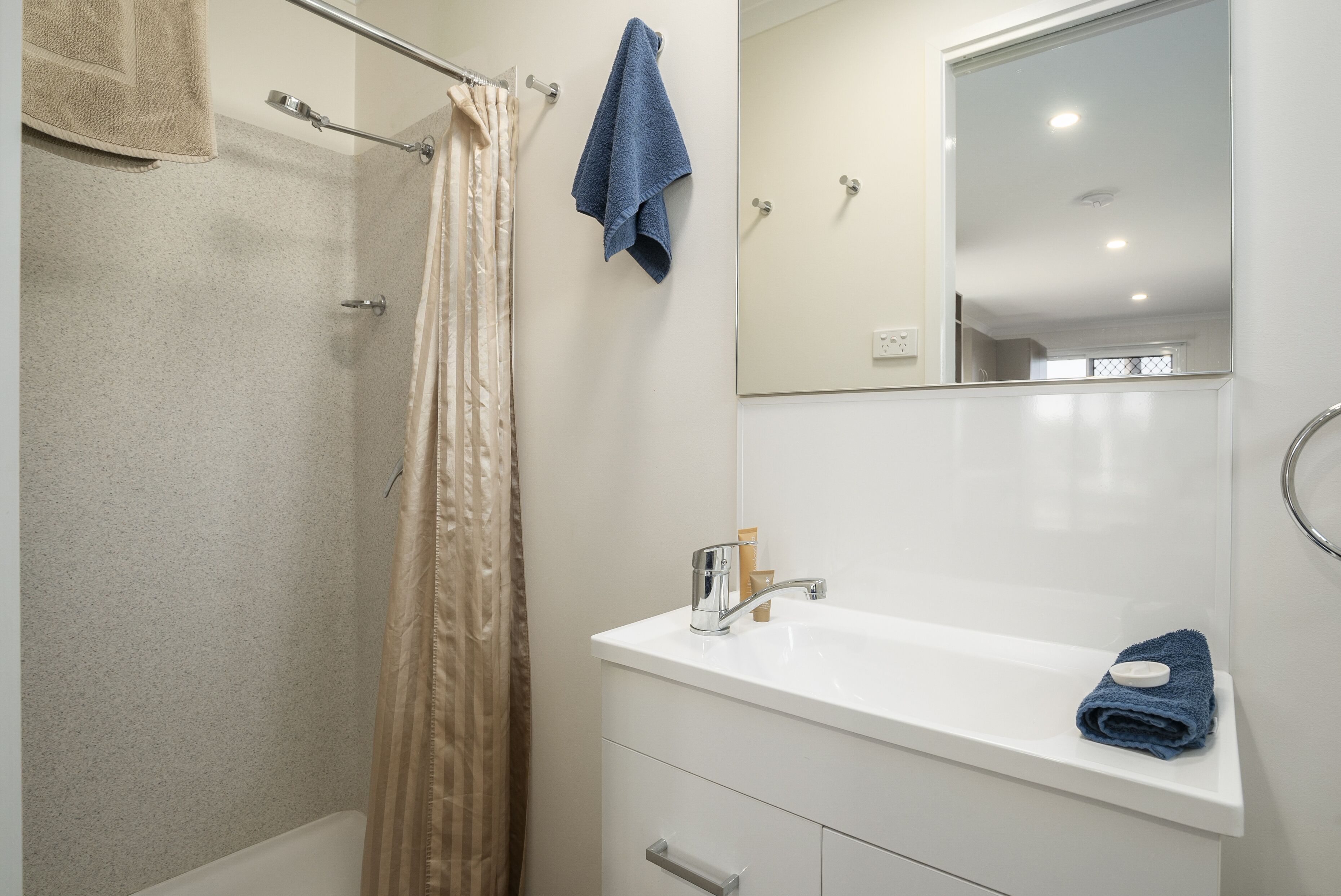 A bathroom with a shower, a sink, and a mirror.