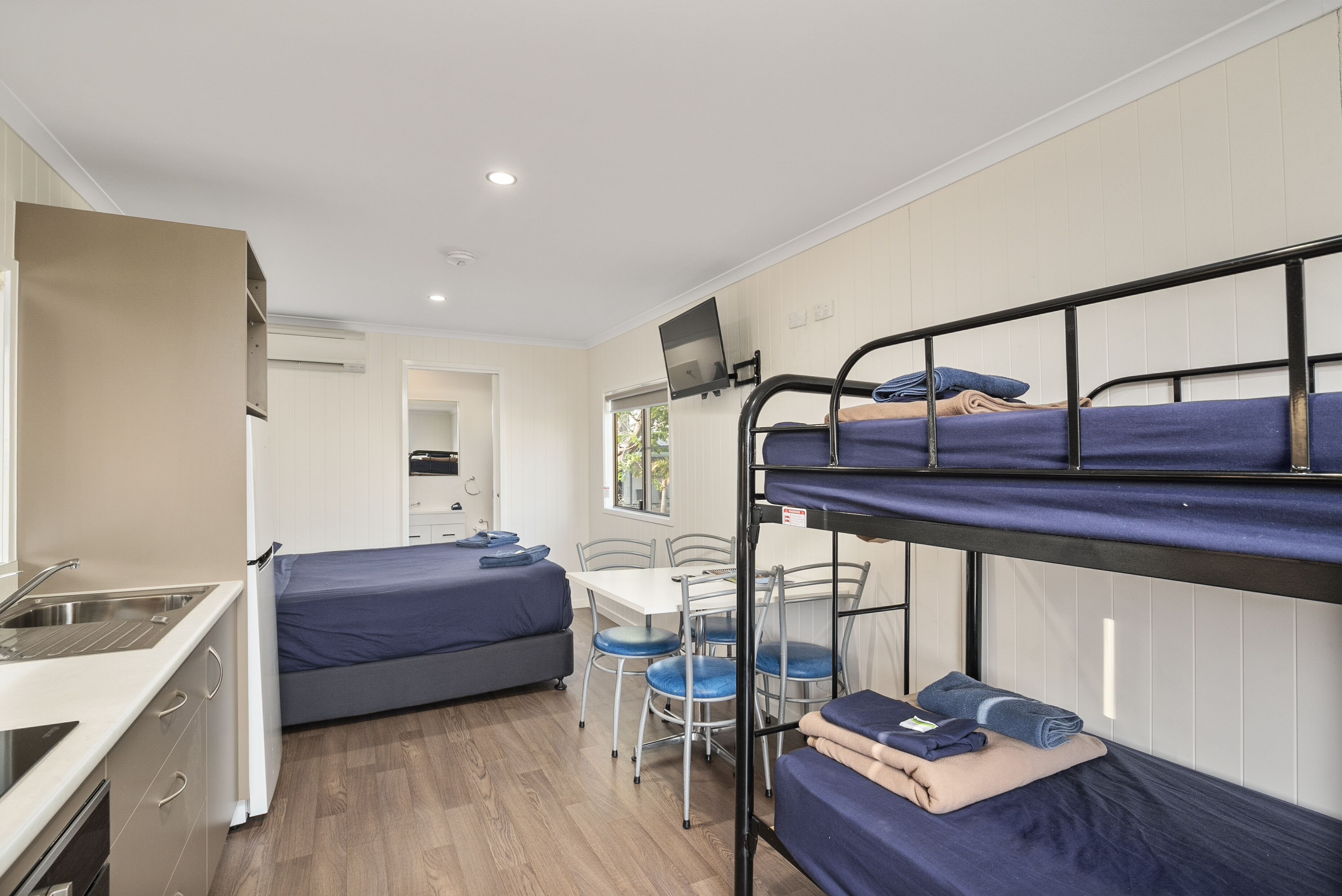 Une pièce compacte avec des lits superposés, une petite kitchenette, une table à manger et un téléviseur.