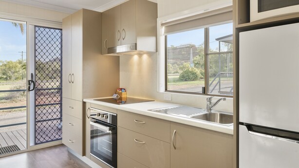 Una cocina moderna con armarios color beige, un lavamanos de acero inoxidable y un horno empotrado.